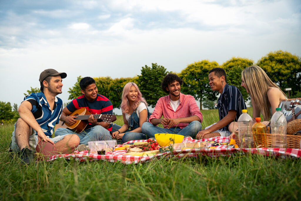 Friends sitting on a blanket in the grass, enjoying a picnic.